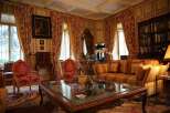 This luxurious living room boasts rich, wood-paneled walls, elegant floral curtains, and antique furnishings.