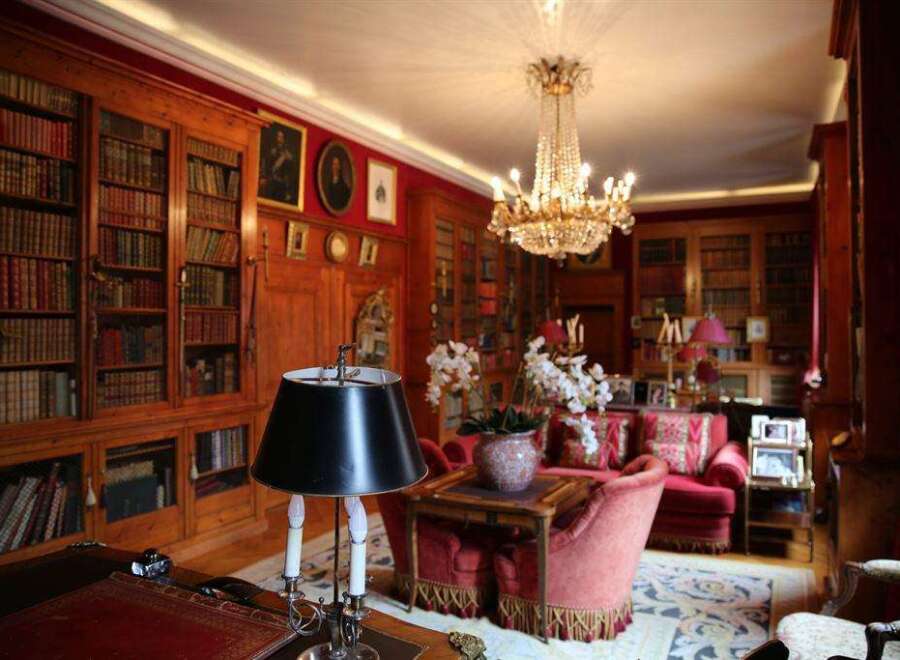 Luxurious library with rich wood paneling, filled with antique books and adorned with a stunning crystal chandelier.