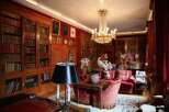 Luxurious library with rich wood paneling, filled with antique books and adorned with a stunning crystal chandelier.