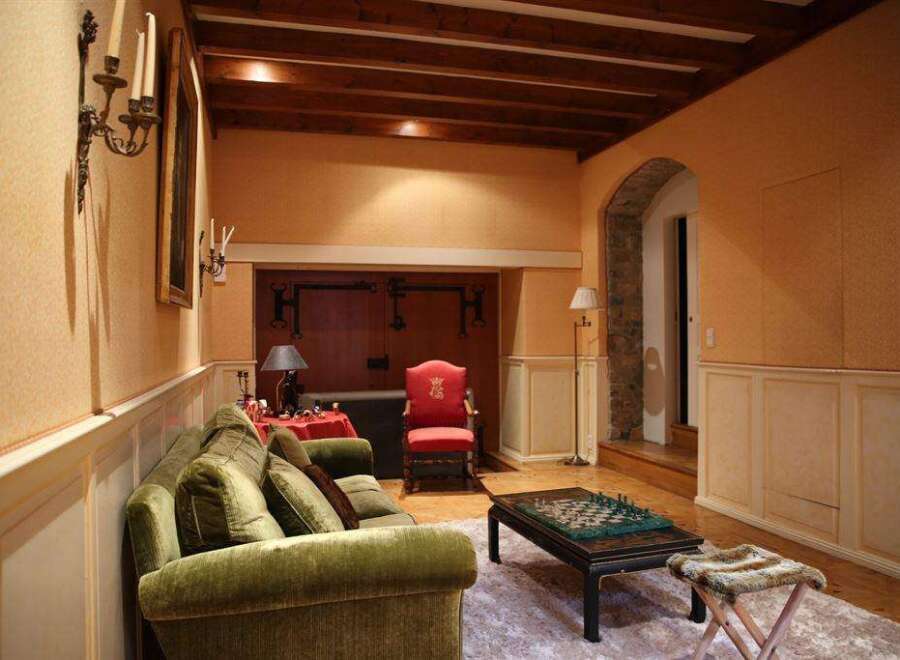 This luxurious living room boasts a stunning wooden beam ceiling, plush velvet sofas, and antique-style decor.