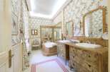 This luxurious bathroom boasts elegant floral wallpaper, antique-style vanities, and a spacious bathtub.