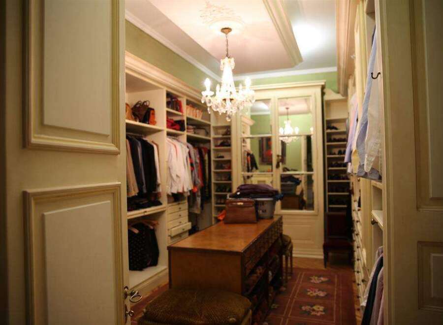 Step into a luxurious walk-in closet featuring custom built-in cabinetry, elegant chandeliers, and ample storage space for all your clothing and accessories.