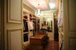 Step into a luxurious walk-in closet featuring custom built-in cabinetry, elegant chandeliers, and ample storage space for all your clothing and accessories.