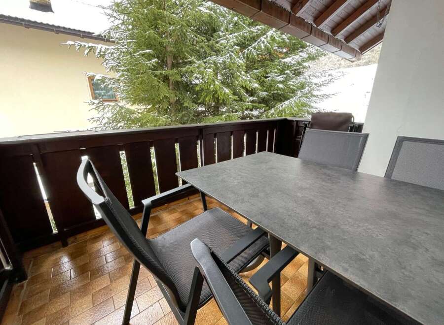 Enjoy the serene beauty of this balcony with a stunning view of snow-covered trees.
