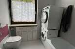 This bathroom features a modern design with a stacked washer and dryer, maximizing space.