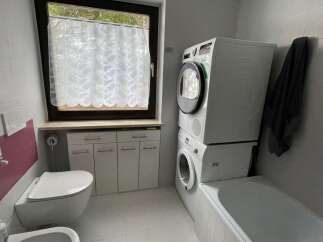 This bathroom features a modern design with a stacked washer and dryer, maximizing space.