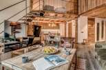 This stunning chalet boasts a spacious open-plan living area with exposed wooden beams and a cozy fireplace, perfect for relaxing after a day on the slopes.