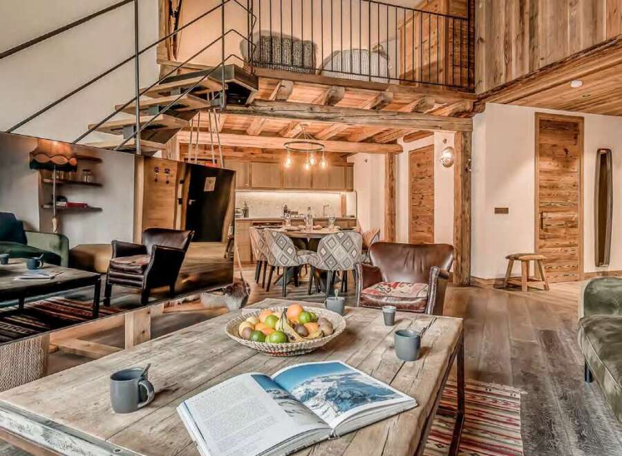 This stunning chalet boasts a spacious open-plan living area with exposed wooden beams and a cozy fireplace, perfect for relaxing after a day on the slopes.