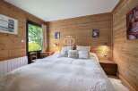 Cozy bedroom with wooden walls and a comfortable bed.