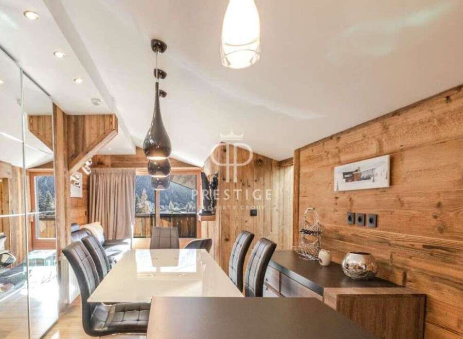 Experience luxury living in this stunning property, featuring a modern dining area with a sleek white table and stylish black chairs.
