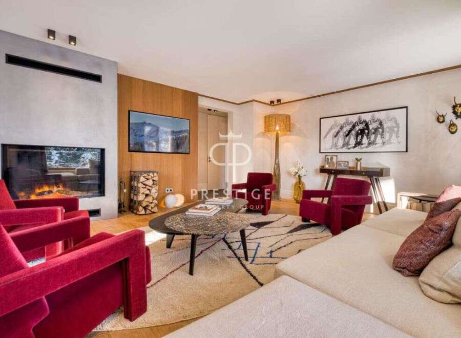 Experience luxury living in this stunning property, featuring a cozy fireplace and elegant red armchairs.