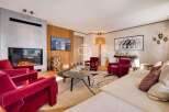 Experience luxury living in this stunning property, featuring a cozy fireplace and elegant red armchairs.