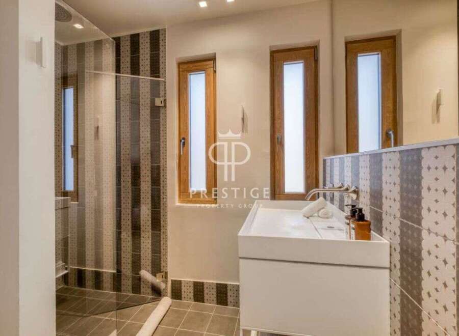 Discover a modern bathroom design with a sleek white vanity and stylish patterned tiles.