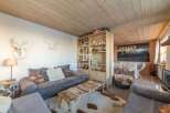 Experience the charm of this cozy living space, featuring a rustic wooden ceiling and a stylish seating area.