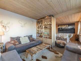 Experience the charm of this cozy living space, featuring a rustic wooden ceiling and a stylish seating area.