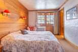 Cozy bedroom with wooden walls and a comfortable bed.