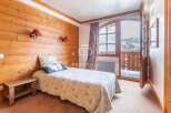 Cozy bedroom with wooden walls and a charming bedspread.
