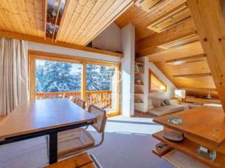Experience the charm of this cozy mountain retreat, featuring stunning views of snow-covered trees through expansive windows.