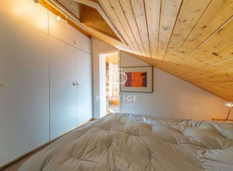 Discover the charm of this cozy bedroom with its unique sloped ceiling and wooden accents.