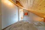Discover the charm of this cozy bedroom with its unique sloped ceiling and wooden accents.