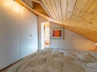 Discover the charm of this cozy bedroom with its unique sloped ceiling and wooden accents.