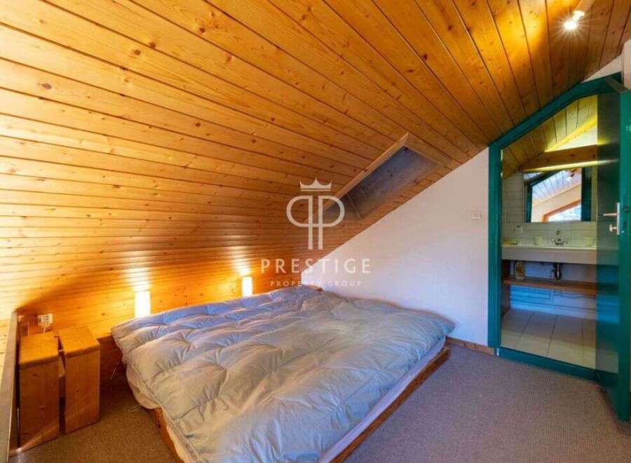 Discover a cozy bedroom with a unique sloped ceiling and wooden accents.