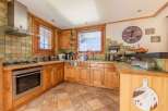 This charming kitchen boasts a warm, inviting atmosphere with its wooden cabinetry and tiled backsplash.