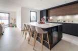 Stunning open-plan kitchen and living area with modern dark cabinetry and a large island.