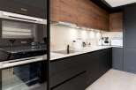 Modern kitchen with sleek black cabinetry and wood accents.