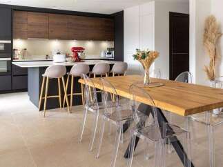 Stunning kitchen with dark cabinetry and wood accents, complemented by a spacious dining area featuring a live-edge wood table and transparent chairs.