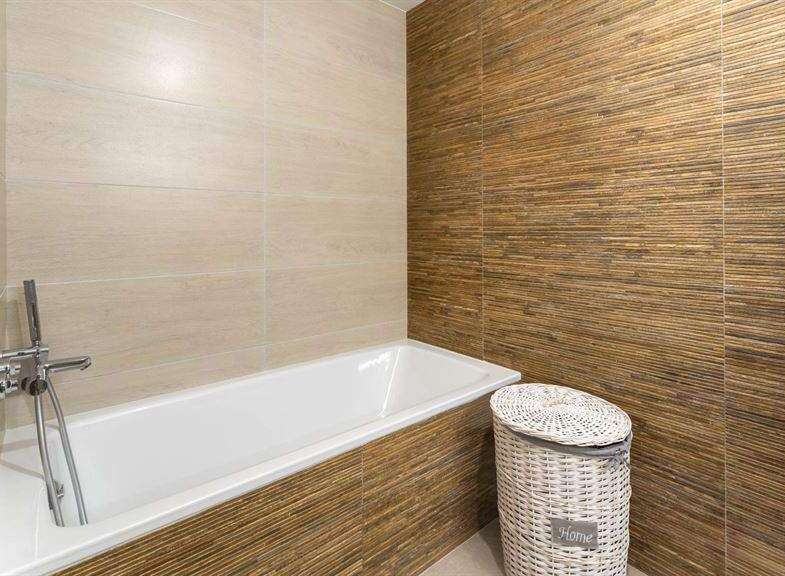 Relax in this modern bathroom featuring a sleek bathtub and stylish bamboo-textured wall tiles.