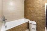 Relax in this modern bathroom featuring a sleek bathtub and stylish bamboo-textured wall tiles.