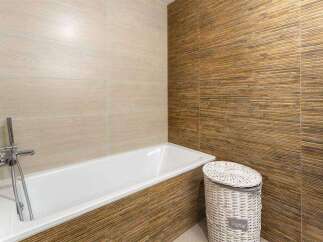 Relax in this modern bathroom featuring a sleek bathtub and stylish bamboo-textured wall tiles.