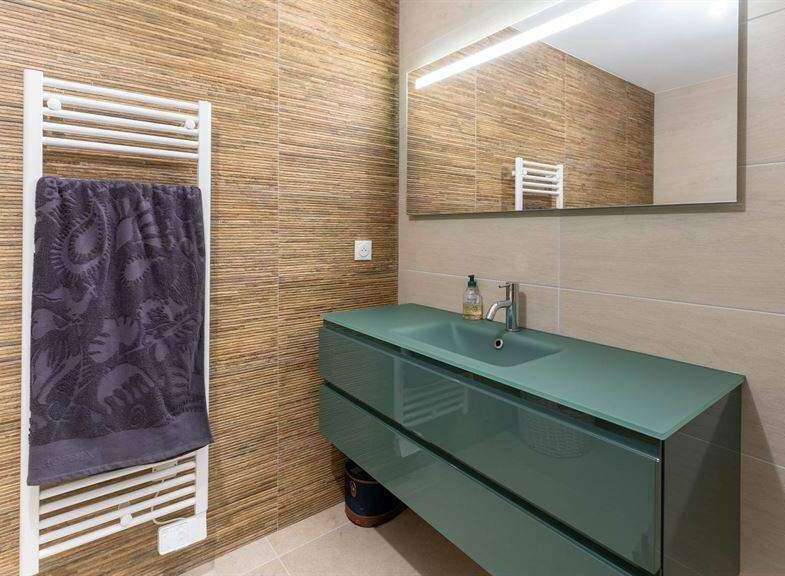 Modern bathroom with teal vanity and glass countertop.