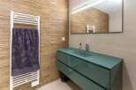 Modern bathroom with teal vanity and glass countertop.