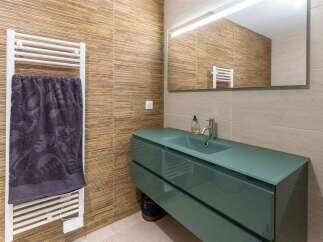 Modern bathroom with teal vanity and glass countertop.