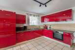 Discover modern living in this stunning kitchen! Featuring sleek red cabinetry, a built-in oven, and ample counter space, this kitchen is perfect for culinary enthusiasts.