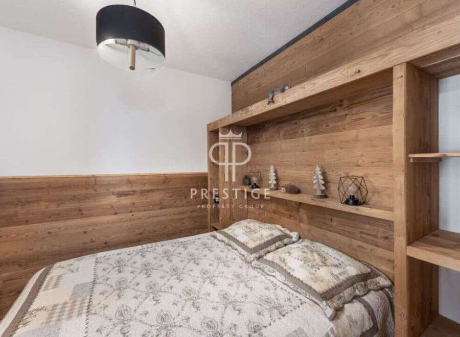 Discover the charm of this cozy bedroom, featuring a unique wooden headboard and built-in shelving.