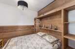 Discover the charm of this cozy bedroom, featuring a unique wooden headboard and built-in shelving.