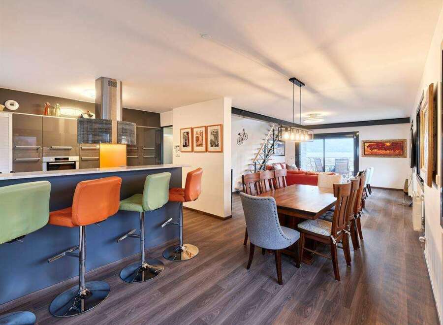 Stunning open-concept living space featuring a modern kitchen with a breakfast bar, seamlessly flowing into a dining area with a wooden table and comfortable seating.
