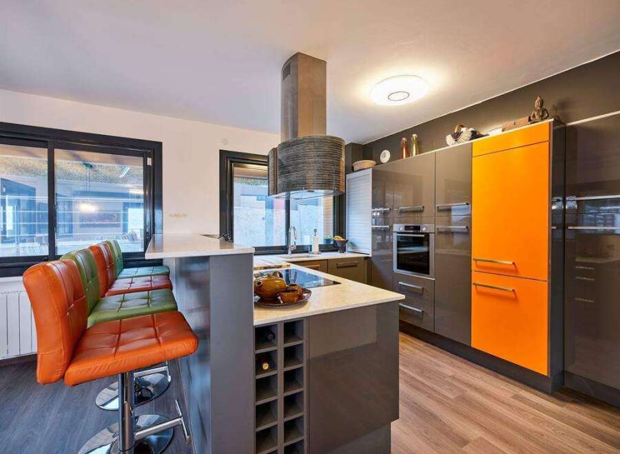 Modern kitchen with orange accents and a breakfast bar.