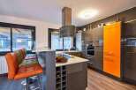 Modern kitchen with orange accents and a breakfast bar.