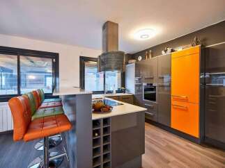 Modern kitchen with orange accents and a breakfast bar.