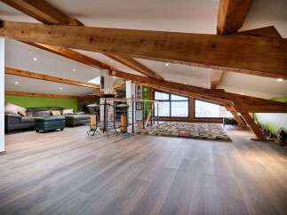 Stunning attic conversion boasts exposed wooden beams and expansive windows offering breathtaking views.