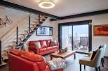 Stunning lake views from this modern living space, featuring a sleek floating staircase and comfortable red leather seating.