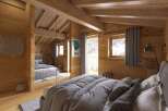 Experience the warmth of this cozy bedroom, featuring stunning wooden paneling and exposed beams.