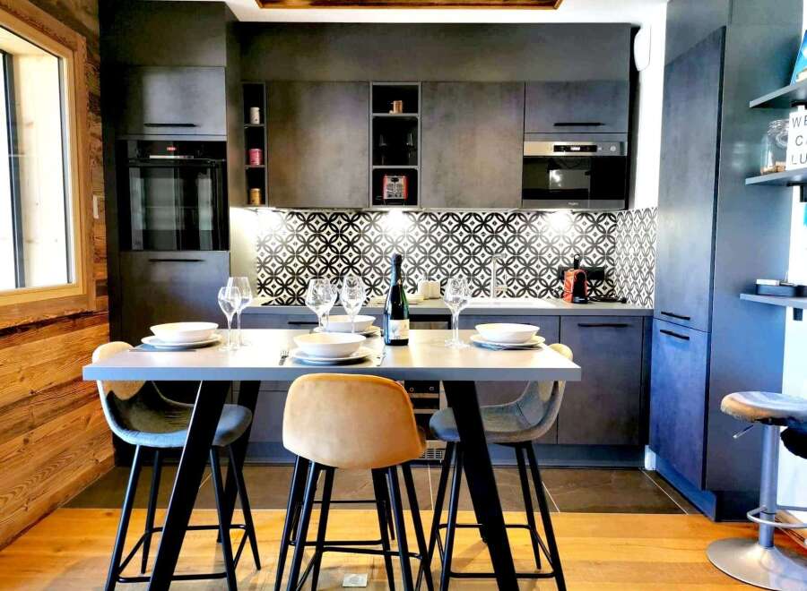 This modern kitchen boasts sleek, dark cabinetry and a stylish geometric backsplash.