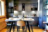 This modern kitchen boasts sleek, dark cabinetry and a stylish geometric backsplash.