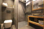 This modern bathroom features a sleek, minimalist design with dark gray tiles and a walk-in shower.