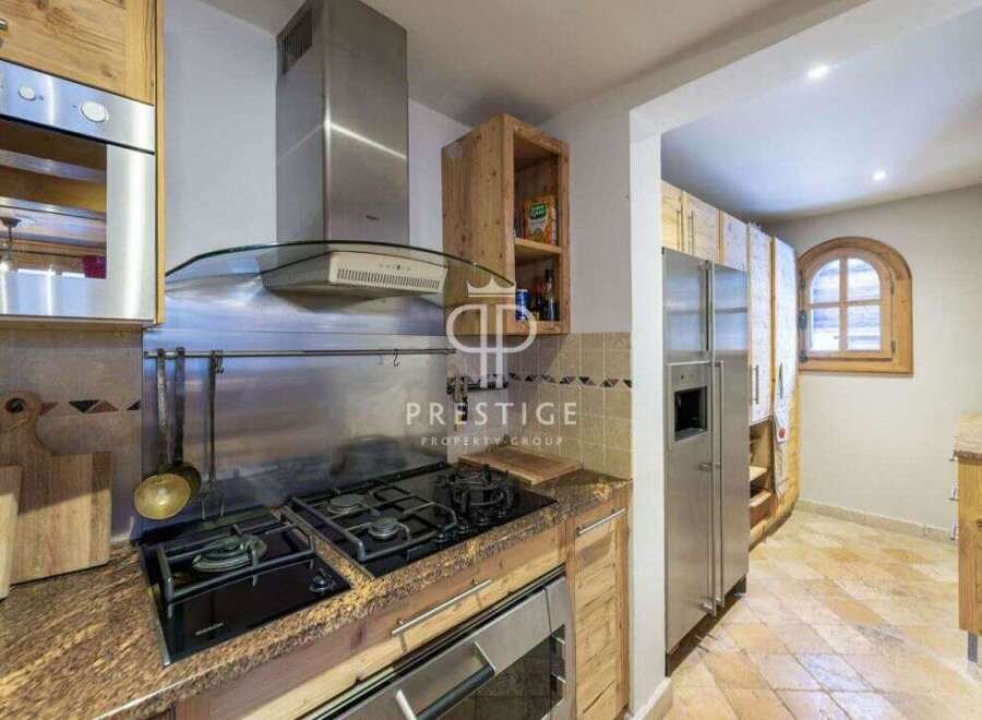 Discover the charm of this kitchen, featuring a stainless steel range hood and a sleek cooktop.